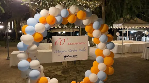 Blue white and orange ballon arch infront of white marquees with tables set up