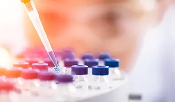 Scientist filling small glass medicine bottles with a pipette